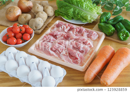 A table full of meat, eggs, and vegetables (pork shoulder, eggs, carrots, peppers, cherry tomatoes, potatoes, onions, and lettuce) 123928859