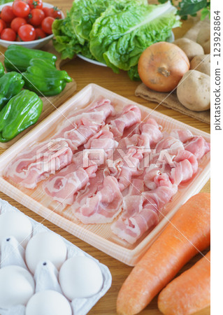 A table full of meat, eggs, and vegetables (pork shoulder, eggs, carrots, peppers, cherry tomatoes, potatoes, onions, and lettuce) 123928864