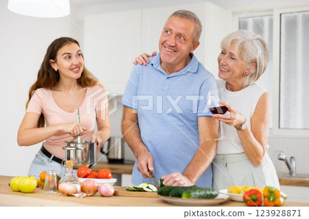 Senior couple spending time together with their adult daughter, cooking delicious meals for dinner 123928871