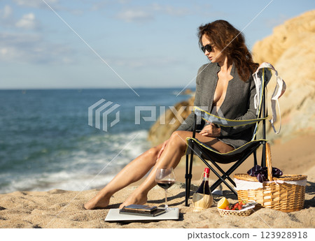 Sexy businesswoman posing naked with picnic basket on seashore on day Sexy businesswoman posing naked with picnic basket on seashore on day 123928918