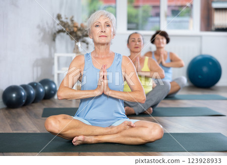 Group of elderly woman doing yoga on mat in studio Group of elderly woman doing yoga on mat in studio 123928933
