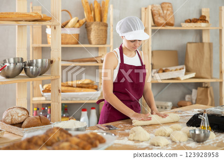 Teenage girl rolls out dough in bakery 123928958