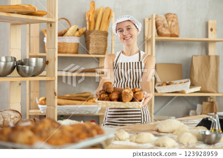 Teen girl holding croissants in square wicker basket 123928959
