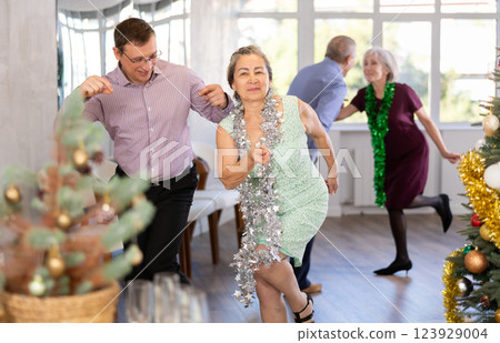 Middle-aged man and elderly woman are dancing contemporary twist in couple in Christmas atmosphere Middle-aged man and elderly woman are dancing contemporary twist in couple in Christmas atmosphere 123929004