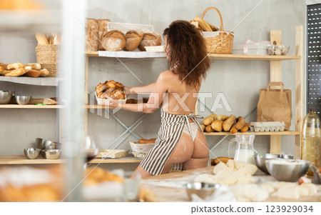 Woman in apron takes croissants from bakery shelf 123929034
