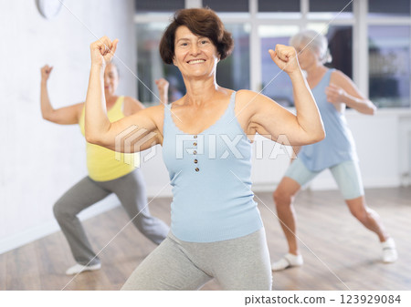 Happy mature woman practicing dance positions during workout session 123929084