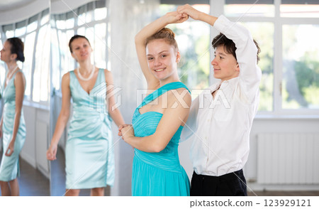 Couple of teenagers in festive clothes learn to dance latin american dance Bachata in studio under the guidance of teacher 123929121
