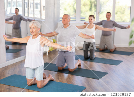 Mature woman bring together and spread your straightened arms at chest level with resistance band 123929127