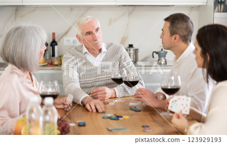 Mature married couples playing card game poker with younger spouses 123929193