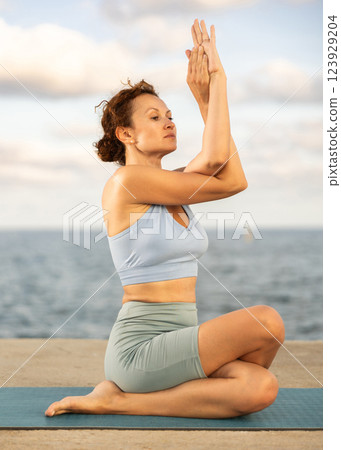 Ardha Matsyendrasana yoga pose - woman doing yoga On beach 123929204