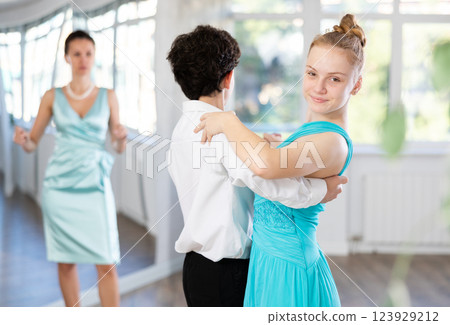Girl and a boy in festive clothes learn to dance tango under guidance of teacher Girl and a boy in festive clothes learn to dance tango under guidance of teacher 123929212
