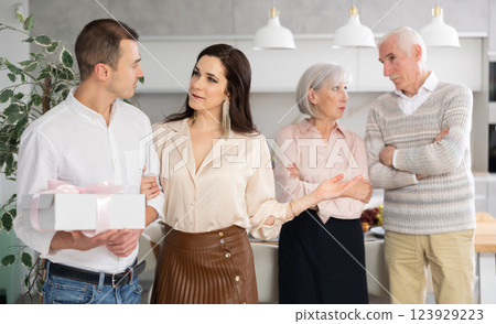 Smiling young couple leaving the house while discontented senior parents standing behind Smiling young couple leaving the house while discontented senior parents standing behind 123929223