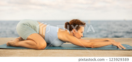 Yoga practice on embankment, female athlete fulfil carry out ashtangasana Yoga practice on embankment, female athlete fulfil carry out ashtangasana 123929389