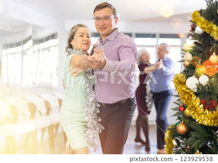 Happy caucasian man and old lady practising paired latin dance in dance studio during celebration Christmas and New Year Happy caucasian man and old lady practising paired latin dance in dance studio during celebration Christmas and New Year 123929538