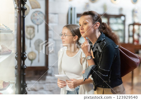 Young woman with teen daughter walk around museum, view antique appliances in museum hall 123929540