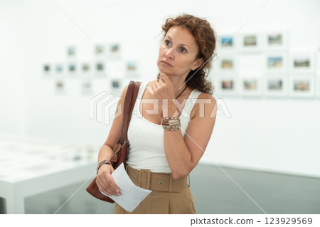 Middle-aged woman looking at pictures on wall in museum Middle-aged woman looking at pictures on wall in museum 123929569