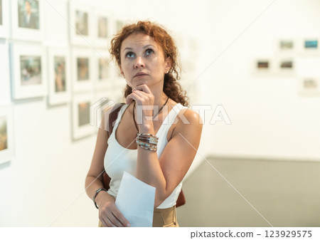 Interested woman studying photos on walls in gallery Interested woman studying photos on walls in gallery 123929575