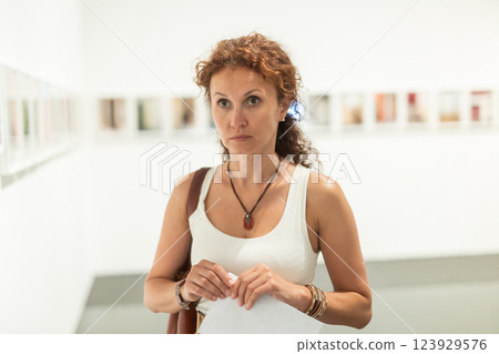 Interested woman studying photos on walls in gallery Interested woman studying photos on walls in gallery 123929576