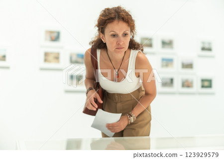 Middle-aged woman looking at objects under showcase in museum Middle-aged woman looking at objects under showcase in museum 123929579