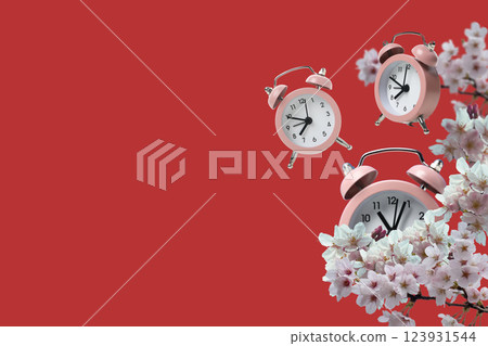 Spring Forward. Pink alarm clocks on a red background, with flowers, with space for text. Spring Forward. Pink alarm clocks on a red background, with flowers, with space for text. 123931544