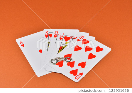 一名因非法賭博而被捕的男子手持撲克牌和手銬的圖片 一名因非法賭博而被捕的男子手持撲克牌和手銬的圖片 123931656