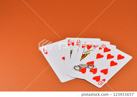 一名因非法賭博而被捕的男子手持撲克牌和手銬的圖片 一名因非法賭博而被捕的男子手持撲克牌和手銬的圖片 123931657