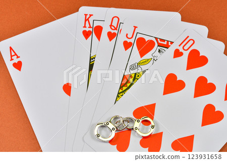 一名因非法賭博而被捕的男子手持撲克牌和手銬的圖片 一名因非法賭博而被捕的男子手持撲克牌和手銬的圖片 123931658