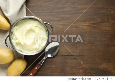 Mashed potatoes in pan, spoon and potatoes on towel on wooden background, space for text 123932182
