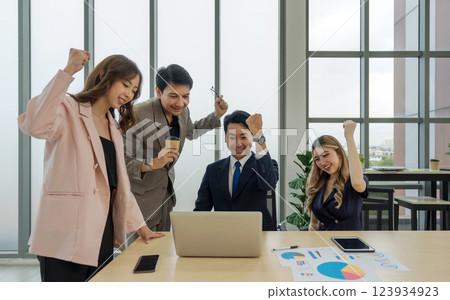 Team of successful business people gather around a table raise their fist up with a smile. Concept of leadership. 123934923