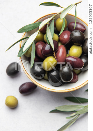 Fresh olives with olive branch in white bowl on marble table Fresh olives with olive branch in white bowl on marble table 123935507