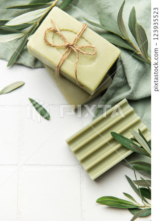 Natural olive soap bars with olive branches on white tiles 123935523