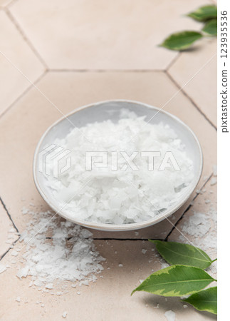 Magnesium chloride flakes in a bowl for spa treatment on tiled surface 123935536