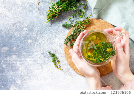Woman holds a hot cup of thyme tea. Top view flat lay. Free space for your text. Woman holds a hot cup of thyme tea. Top view flat lay. Free space for your text. 123936106