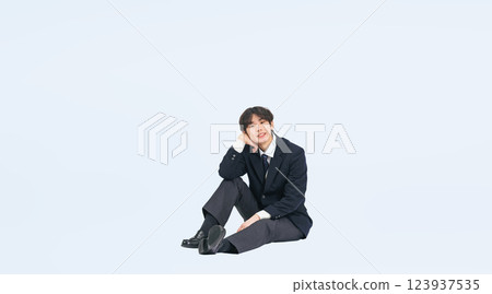 Full-body photo of a male student in uniform sitting 123937535