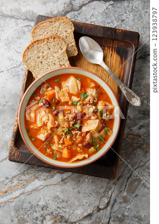 Beef and Cabbage soup is filled with seasoned ground beef, cabbage, carrots, celery, kidney beans, and diced tomatoes closeup in the plate. Vertical top view 123938797