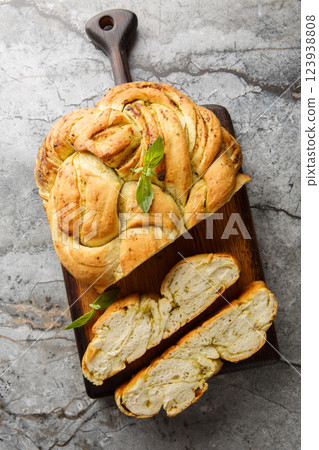 Homemade bread is braided with basil pesto closeup on the wooden board. Vertical top view 123938808