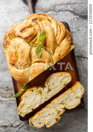 Delicious Pesto Bread is a soft and fluffy homemade bread that has swirls of fragrant basil pesto throughout closeup on the wooden board. Vertical top view 123938809