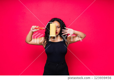 Happy young African woman with paintroller, toothy smile during home renovation 123939456