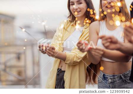 Two cute guys and two charming girls are holding sparklers and smiling Two cute guys and two charming girls are holding sparklers and smiling 123939542