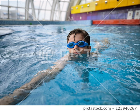 A smiling boy in the pool, a child in swimming glasses. An active child at the water park 123940267
