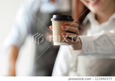 Sustainable Coffee and Personal Touch. A barista proudly presents a takeaway coffee cup to a satisfied customer. 123940377