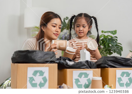 Sustainable Practices and Learning Together. A mother and daughter engage in recycling, discovering the importance of eco-friendly habits. Sustainable Practices and Learning Together. A mother and daughter engage in recycling, discovering the importance of eco-friendly habits. 123940386
