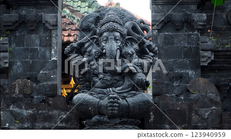 An old hindu stone statue of Ganesha covered with moss, standing on the str.. 123940959