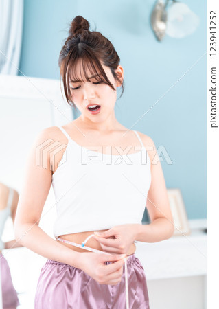 Young woman surprised by measuring her waist 123941252