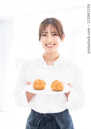 A young pastry chef smiling in front of a cream puff 123941259