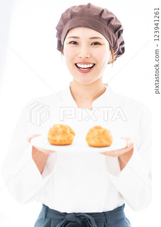 A young pastry chef smiling in front of a cream puff A young pastry chef smiling in front of a cream puff 123941261