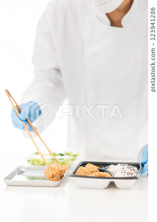 Young woman packing side dishes at a food factory, faceless 123941286