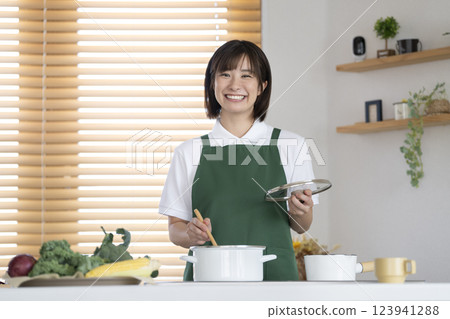家事服務圖片:一位 30 多歲的女士正在做飯,面帶微笑,看著鏡頭 家事服務圖片:一位 30 多歲的女士正在做飯,面帶微笑,看著鏡頭 123941288