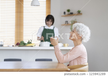 一名 30 多歲的女性在廚房做飯,一名老年女性正在休息。 一名 30 多歲的女性在廚房做飯,一名老年女性正在休息。 123941289