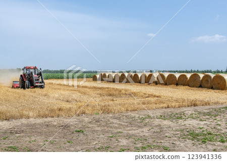 Hokkaido in summer: wheat culm rolls and working machines (Hokkaido image) Hokkaido in summer: wheat culm rolls and working machines (Hokkaido image) 123941336